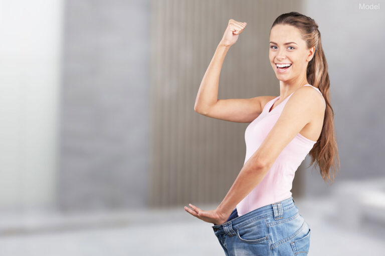 A woman is happy about losing weight and is showing off her new, smaller size jeans.